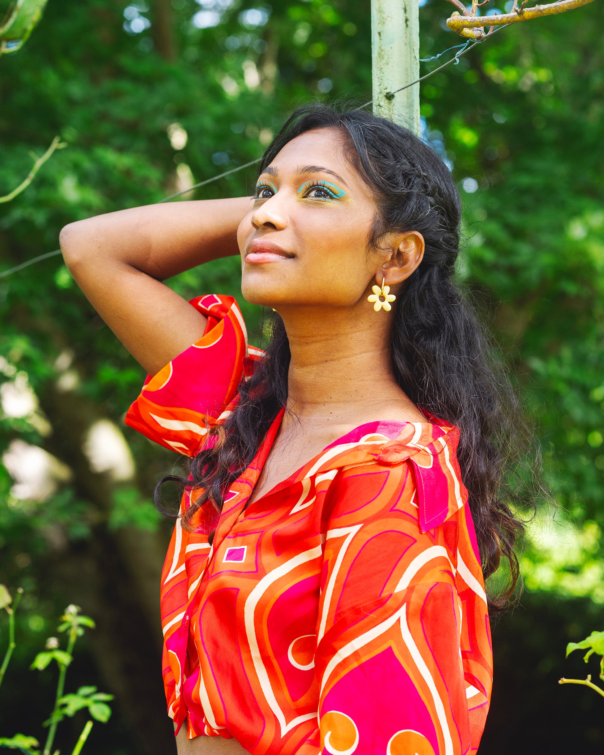 femme indienne dans un jardin et portant des boucles d'oreilles jaunes en forme de fleur de jasmin en argile polymère faites à la main