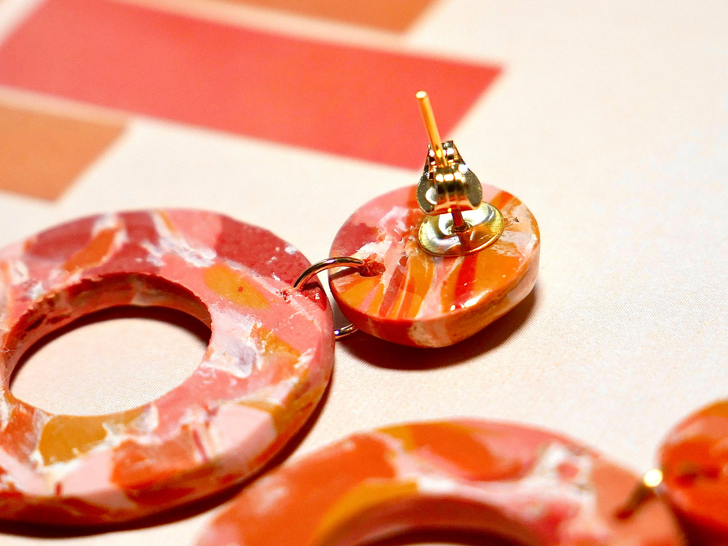 boucle d'oreille composée d'un rond et un grand cercle marbrés orange, rouge et rose, fait main, montrant l'arrière avec l'attache et lacier inoxydable