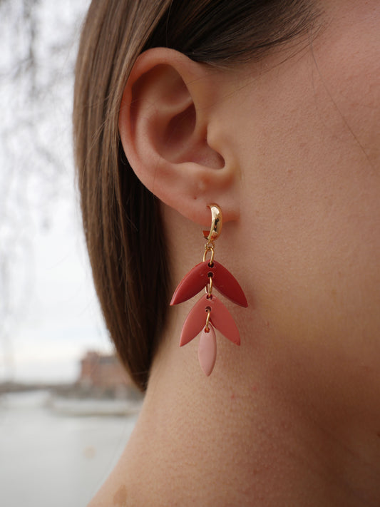 visage de femme de profil portant une boucle d'oreille fantaisie aux couleurs rouges et roses dégradées, et divisées en trois parties, le tout en forme de goutte, en argile polymère et faite main