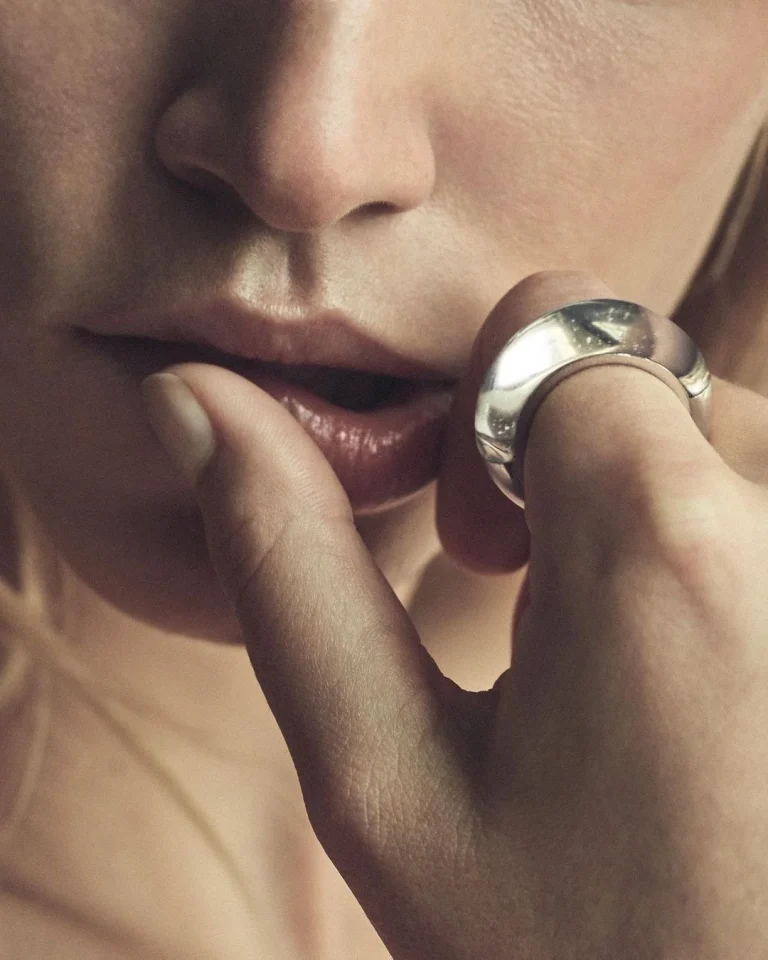 Bouche et main portant une large bague en argent, doigt posé sur la lèvre