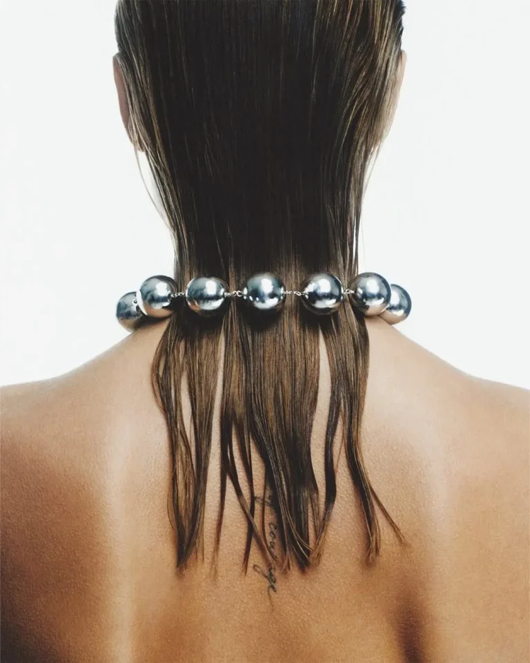 Nuque de dos, cheveux relevés, portant un collier de grosses perles argentées