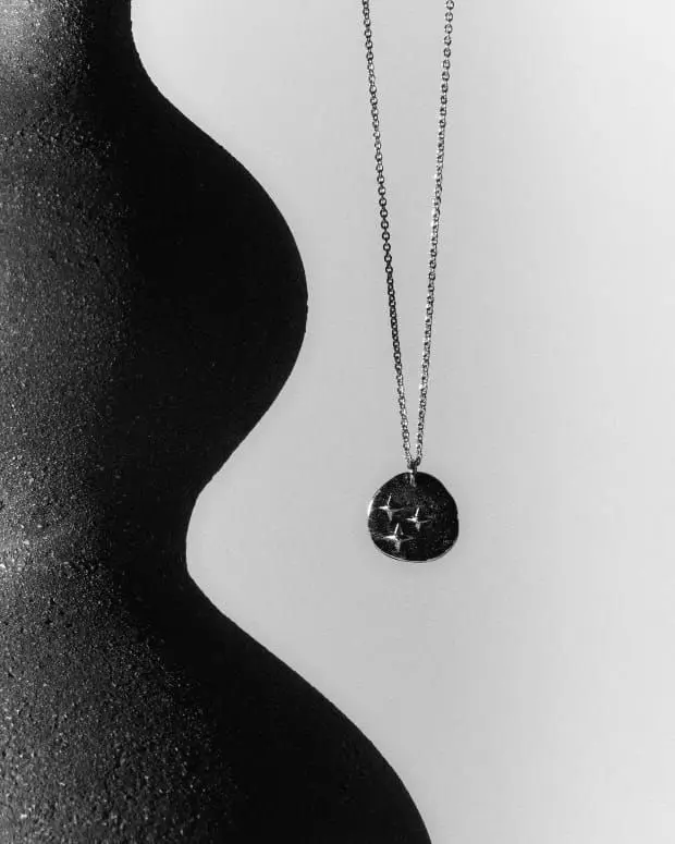 Collier à pendentif rond en argent noirci, porté le long d'une nuque, en noir et blanc