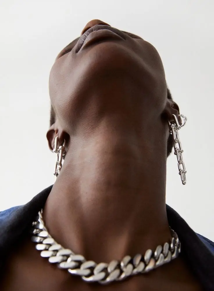 Femme la tête renversée en arrière, portant un collier à maillons épais et des boucles pendantes en argent