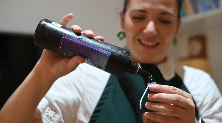 Femme versant un liquide dans un petit flacon, en atelier